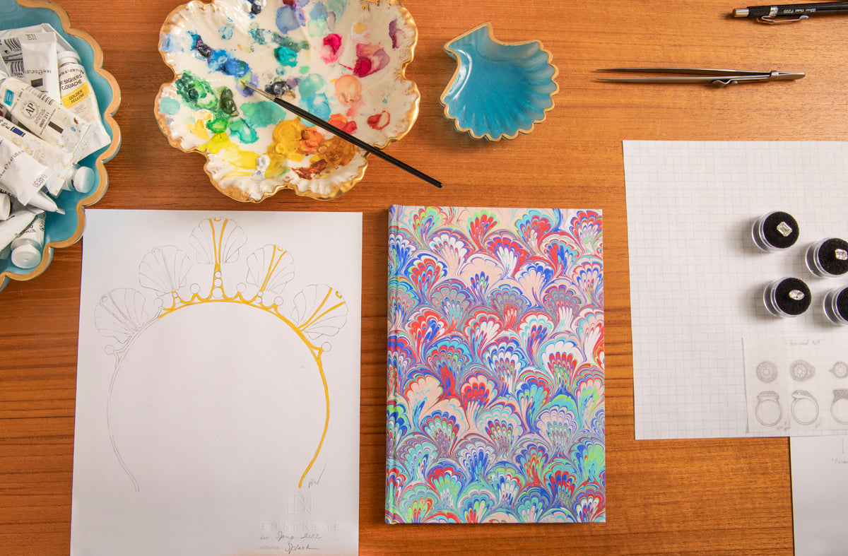 Brent Neale Winston's design table, with a hand-drawn jewel, paint palette, and color references
